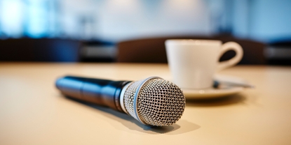 Conferencia de prensa: micrófono y taza de café sobre una mesa.